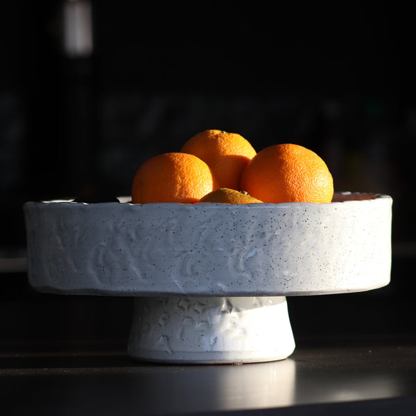 white textured bowl made from terracotta sits on black table with oranges in it