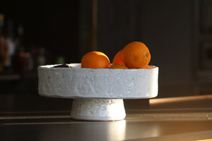 white textured bowl made from terracotta sits on brown table with oranges in the bowl