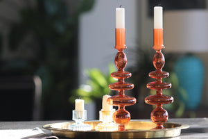 Two Orange bobble glass candlestick holders sat in a gold tray with artwork in background