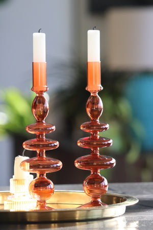 Two Orange bobble glass candlestick holders sat in a gold tray 