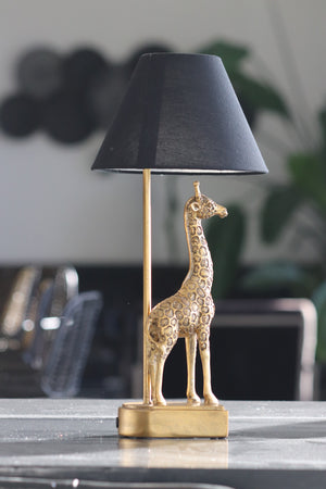 gold coloured giraffe table lamp with black shade on table 