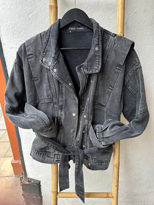 Faded Black denim jacket with 80s design lapels.  Arms tucked into pockets and belt tied up. Jacket is hung on a ladder