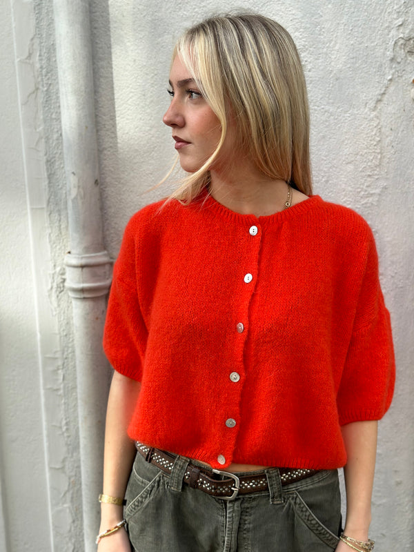 A blonde model wears a mohair mix poppy red cardigan with three quarter length sleeves