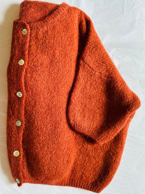 folded rust coloured mohair mix cardigan on a white background