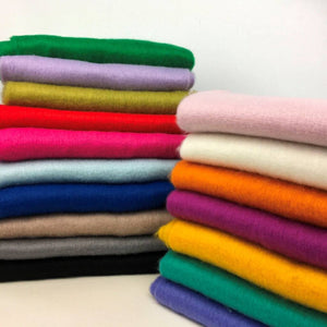 A pile of bright coloured folded scarves in multiple different colours