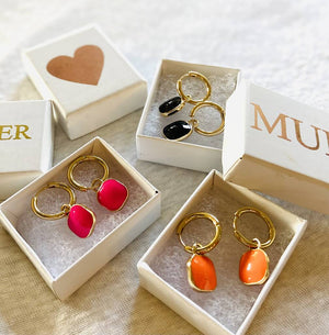 3 sets of colour pop earrings sitting in open gift boxes.  Gold hoops with enamel square colour pops in pink, orange and black with gift box with heart, sister and mum written in gold on the lid