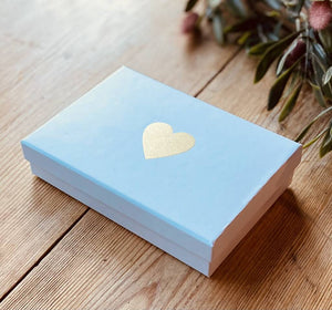 blue cardboard gift box with gold heart embossed in the middle of the lid