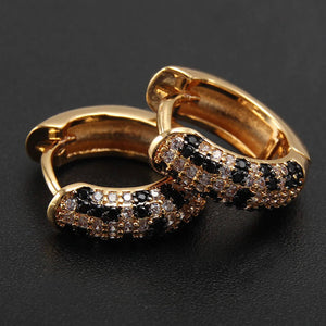 close up of gold wide hoop small earrings with a black and crystal effect on one edge of the earring.