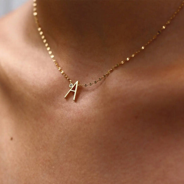 Personalised Gold Letter And Diamond Necklace sitting on the neck.  The letter A is shown. Gold chain with diamond sitting next to the letter