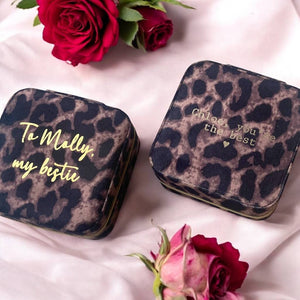 Two leopard print zip jewellery cases sit side by side with gold embossed messages on each one.  