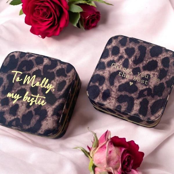 Two leopard print zip jewellery cases sit side by side with gold embossed messages on each one.  