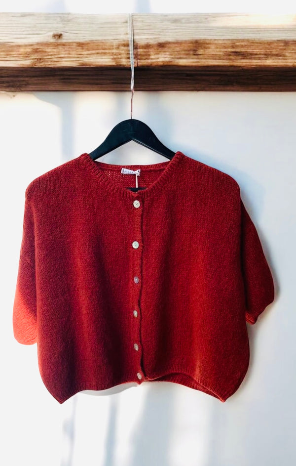 rust coloured mohair mix cardigan with three quarter bell sleeve hanging from a wooden beam